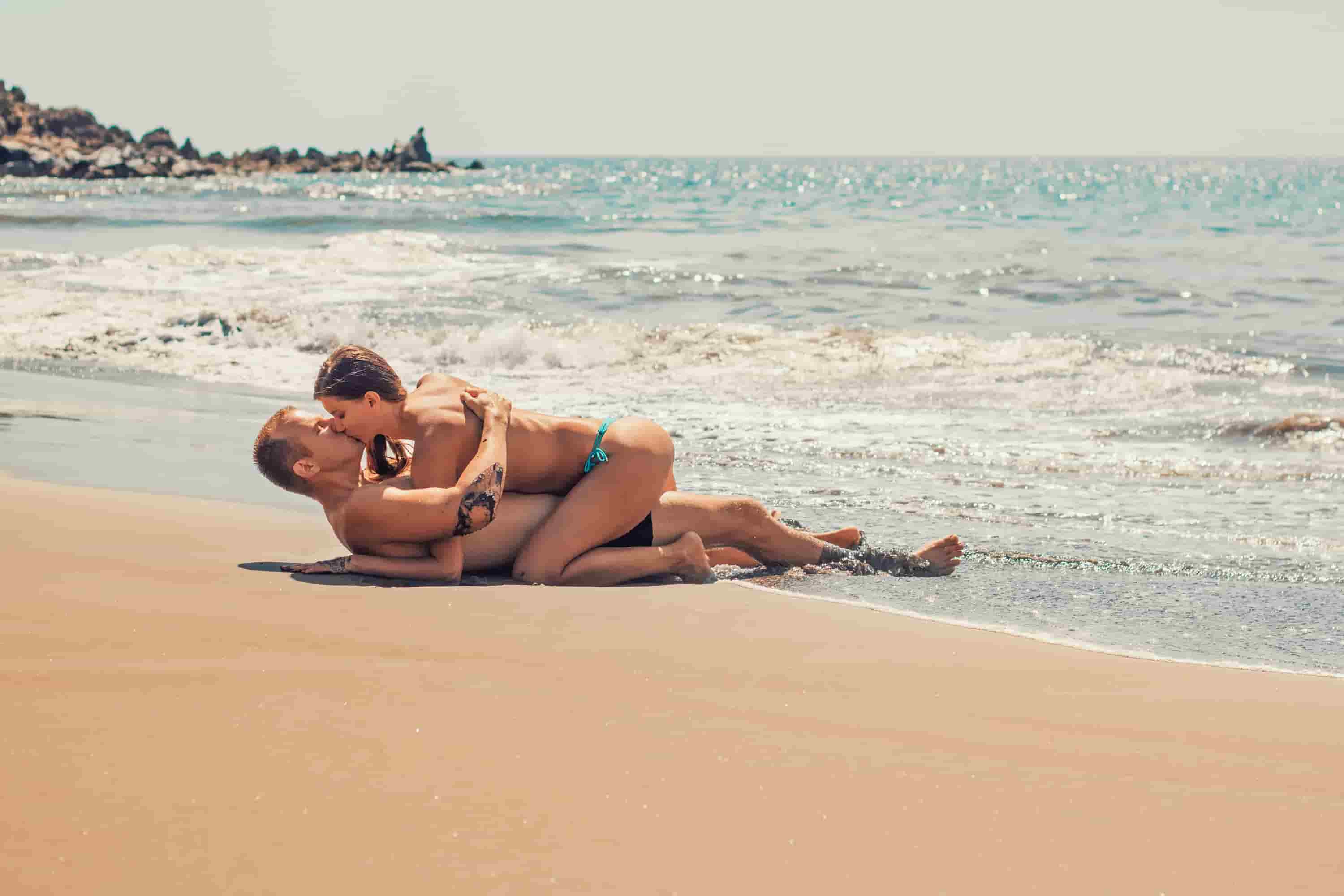 海で金髪の男と美女がキスをしている